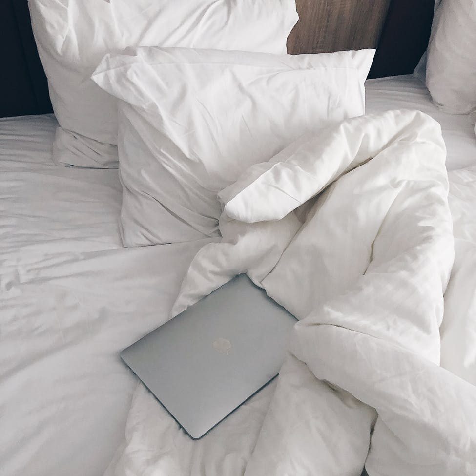 laptop on unmade bed in morning